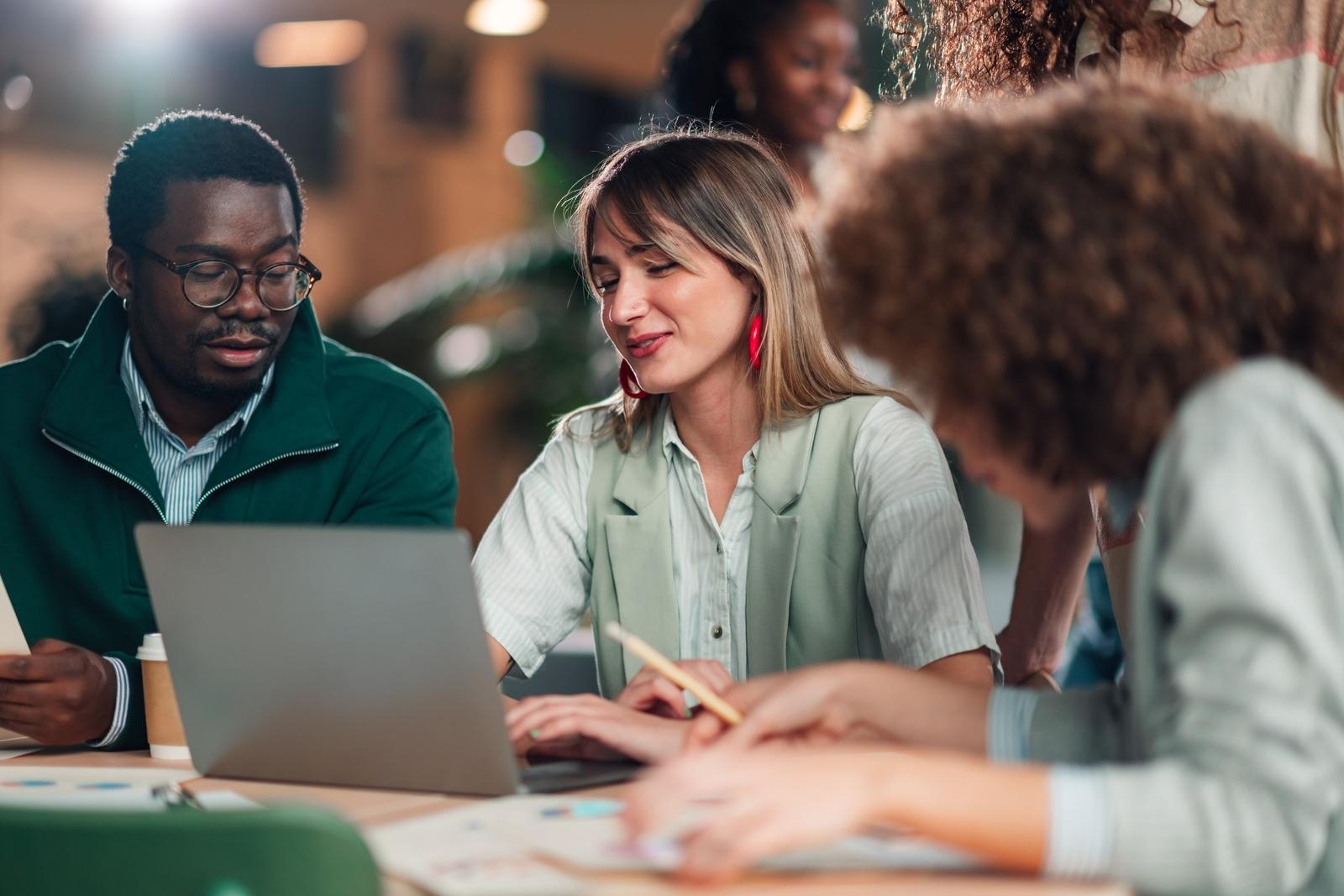 A business team collaborating around a laptop