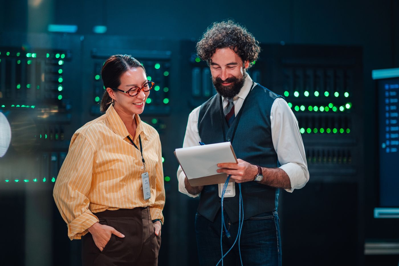 Two technicians reviewing network equipment in a server room